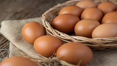 Cesta de huevos morenos, tres de ellas fuera de la misma.