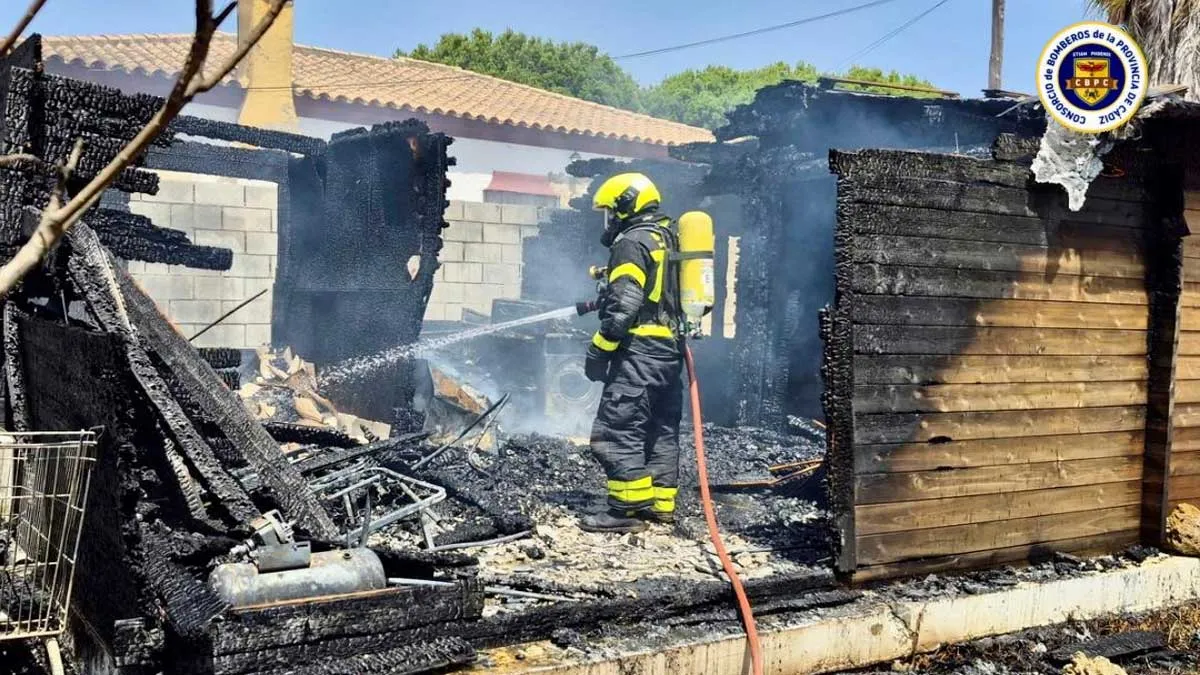 Bombero equipado con extintor apagando fuego en el interior de una casa de madera.