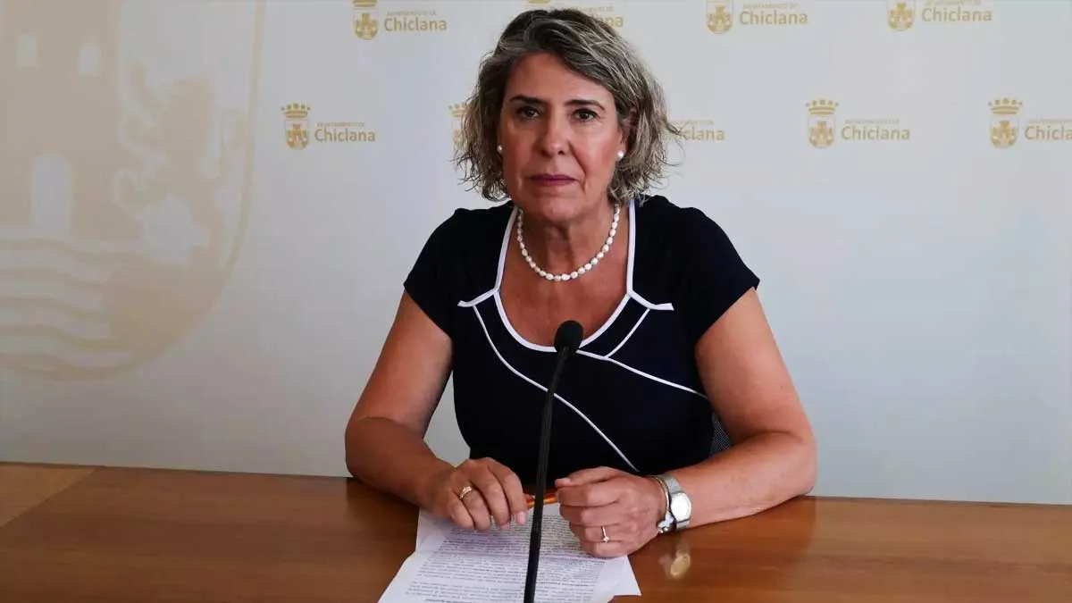 Mari Ángeles Martínez Rico con vestido negro y adornos blancos sentada en una mesa.