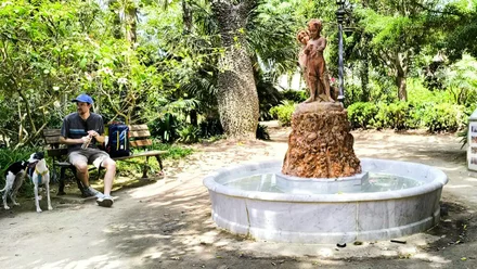 Escultura de los Niños del Paraguas en el Parque Genovés, en banco a la izquierda un hombre y un perro