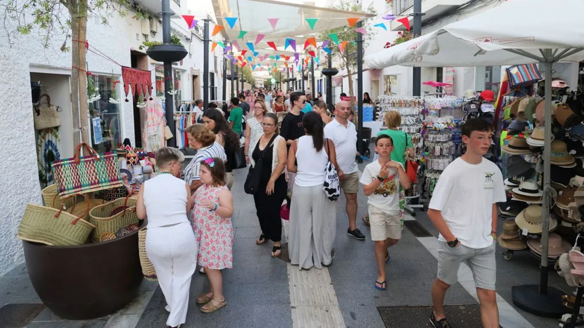 Calle de Rota con un mercadillo de tiendas por el hay muchas personas.