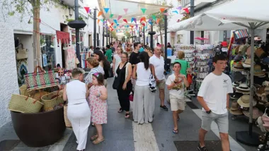 Calle de Rota con un mercadillo de tiendas por el hay muchas personas.