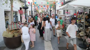 Calle con muchas personas mirando los tenderetes con productos de los comercios en Rota.