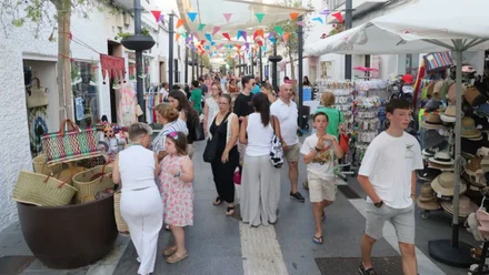 Calle con muchas personas mirando los tenderetes con productos de los comercios en Rota.