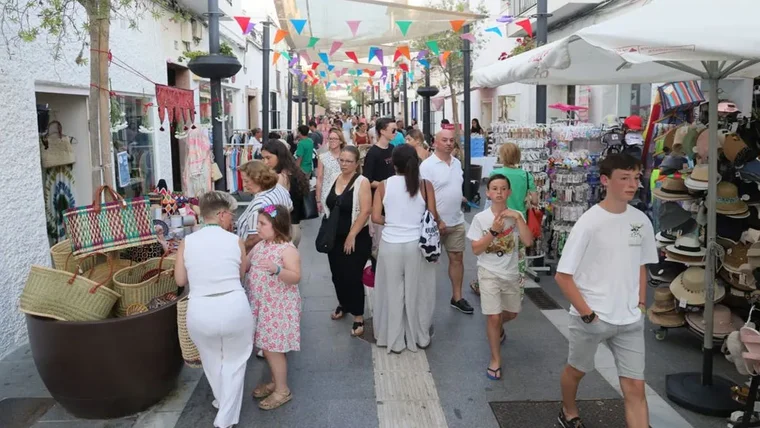 Calle con muchas personas mirando los tenderetes con productos de los comercios en Rota.