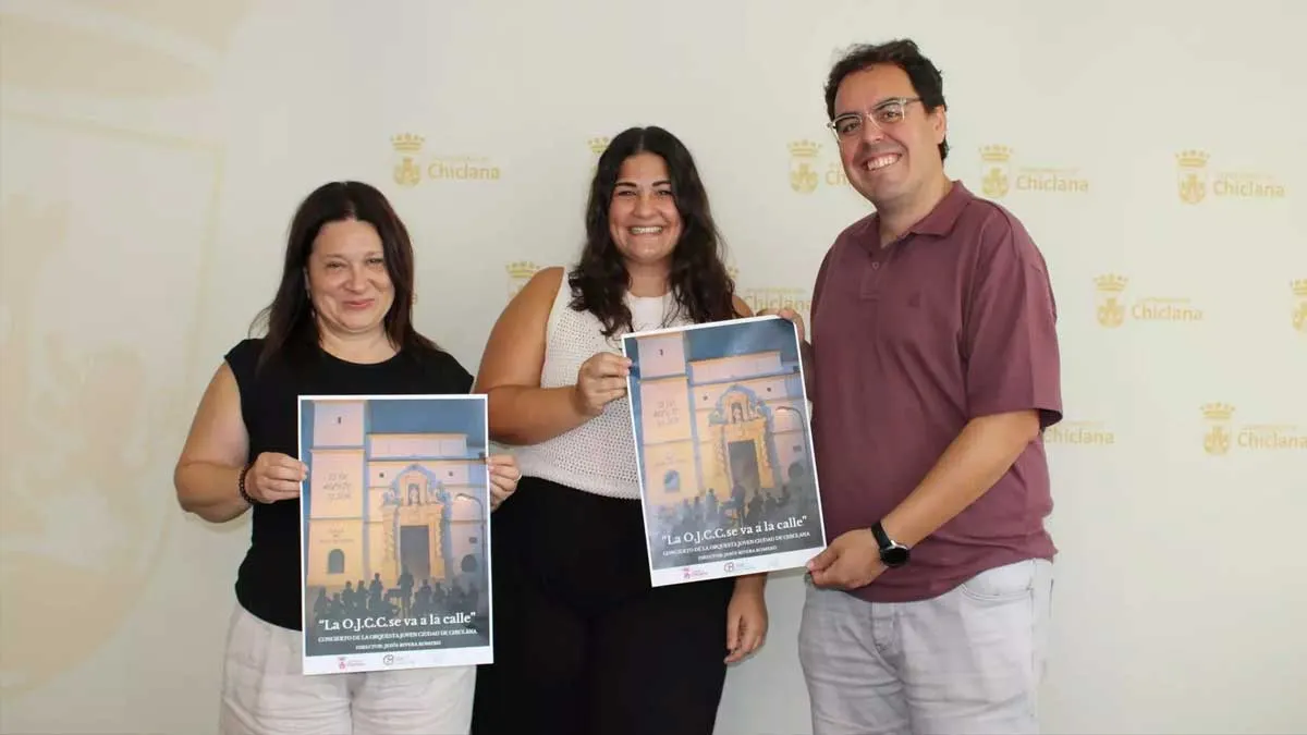 Los organizadores del concierto de la Orquesta Juvenil posan con el cartel del concierto de Chiclana.