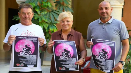 Miembros del Ayuntamiento y organizadores con el cartel en las manos, en tonos negro y rosado.