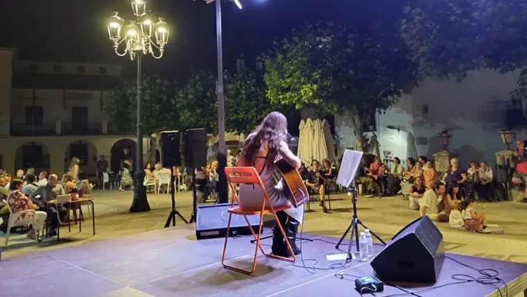 Chica tocando la guitarra en un escenario.