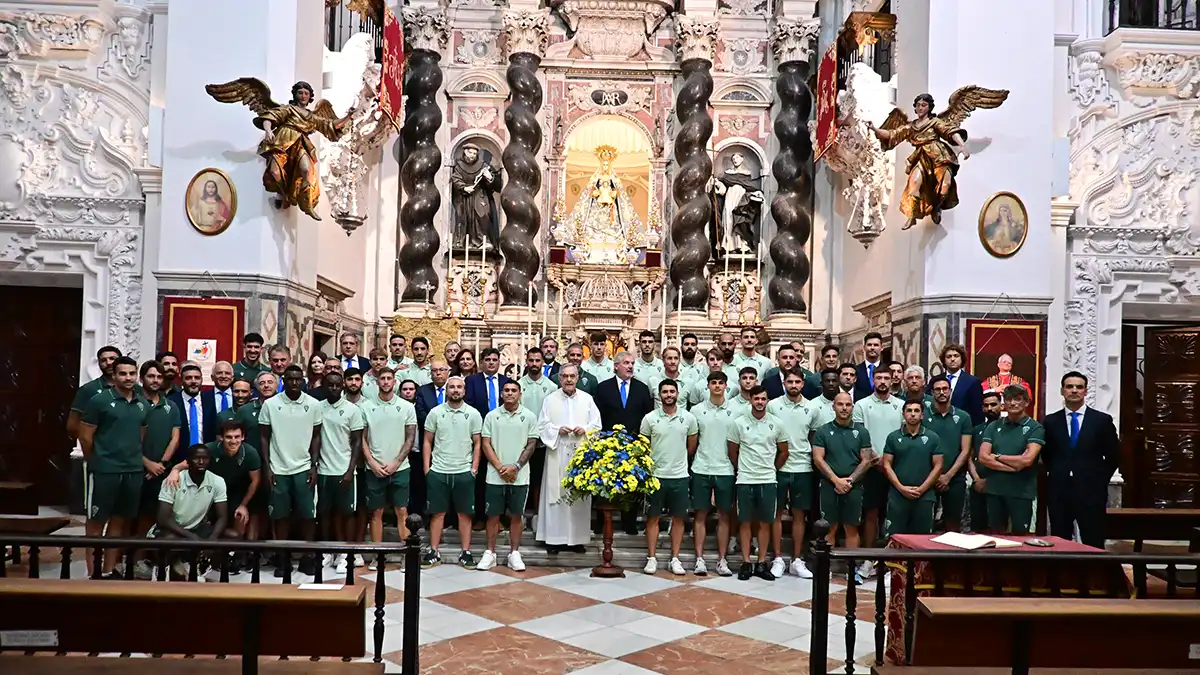 Jugadores, cuerpo técnico y directivos del Cádiz CF posan en grupo frente al altar de la iglesia de Santo Domingo, con la imagen de la Patrona al fondo.