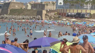 Playa de Santa María del Mar en Cádiz abarrotada de bañistas bajo sombrillas de colores. El mar en calma y el cielo despejado completan la imagen de un día de calor sofocante en la ciudad.