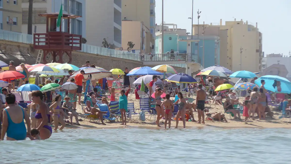 Imagen tomada desde el agua en la playa de la Victoria, en Cádiz, con varias personas disfrutando del baño. El mar en calma y el cielo despejado anticipan que este rincón será un refugio para escapar del intenso calor previsto en los próximos días.