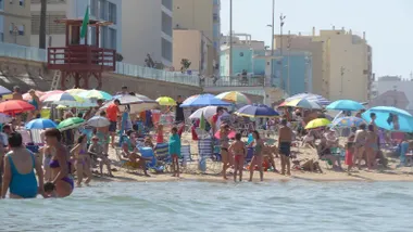 Imagen tomada desde el agua en la playa de la Victoria, en Cádiz, con varias personas disfrutando del baño. El mar en calma y el cielo despejado anticipan que este rincón será un refugio para escapar del intenso calor previsto en los próximos días.