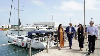 Consejera de la Junta de Andalucía, junto a otras personalidades, en el puerto de Chipiona, están en el muelle y hay barcos.