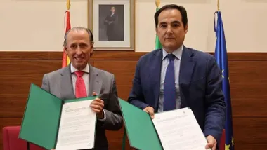 Román y Nieto muestran en sus manos una carpeta verde con el acuerdo firmado.