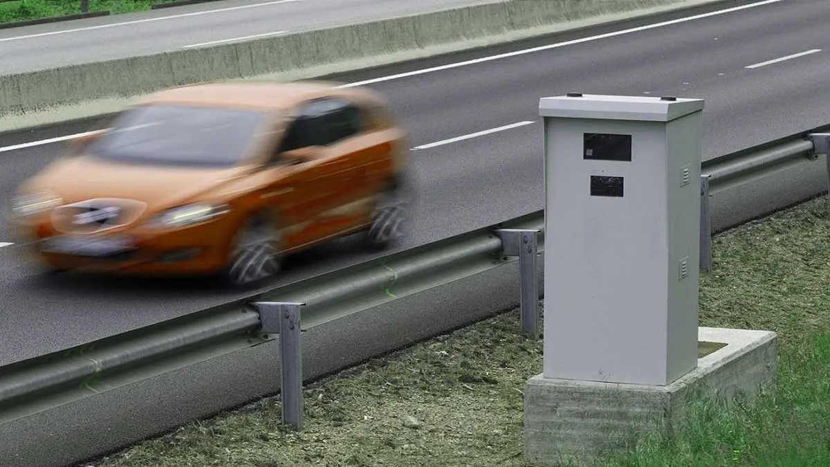 Radar de control de velocidad y coche anaranjado pasado a su lado.