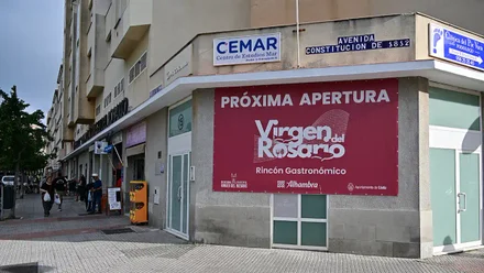 Cartel colocado en la fachada del Mercado Virgen del Rosario de Cádiz que anuncia la apertura de un rincón gastronómico. Se ve la entrada principal del edificio y el rótulo informativo sobre la nueva oferta.