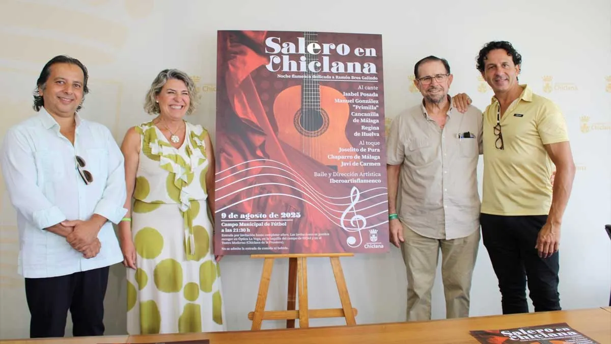 Martínez Rico, con vestido claro estampado, junto al cartel de "Salero en Chiclana" y los organizadores.