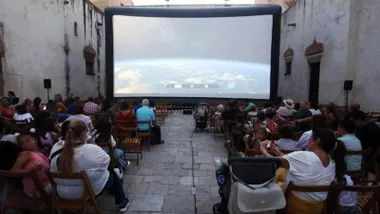 Pantalla de cine y público sentado en el Castillo de San Romualdo en San Fernando.