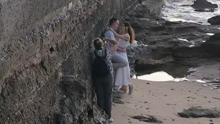 Pareja vestida de novios sobre las rocas de La Caleta, en Cádiz, durante una sesión de fotos en el paseo Fernando Quiñones.