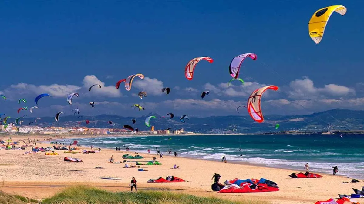 Muchas personas con paracaídas de colores practicando el KiteSurf.