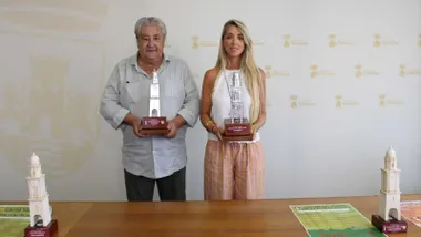 A la izquierda Francisco Cordero, con camisa blanca, junto a la delegada Isabel Butrón, también de blanco y pantalón naranja, ambos portan el trofeo en sus manos.