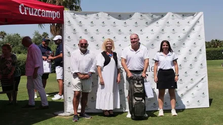 Organizadores posan en el campo de golf, destacan los tonos blancos sobre el césped.
