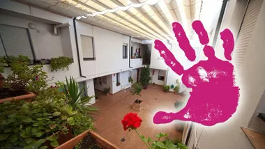 Patio de una casa de acogida y mano en morado contra la violencia de género.