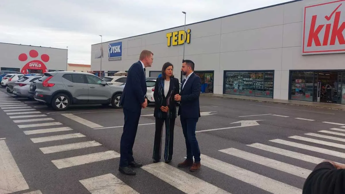 Patricia Cavada, con traje negro, en Zona Franca, tras ella diferentes comercios.