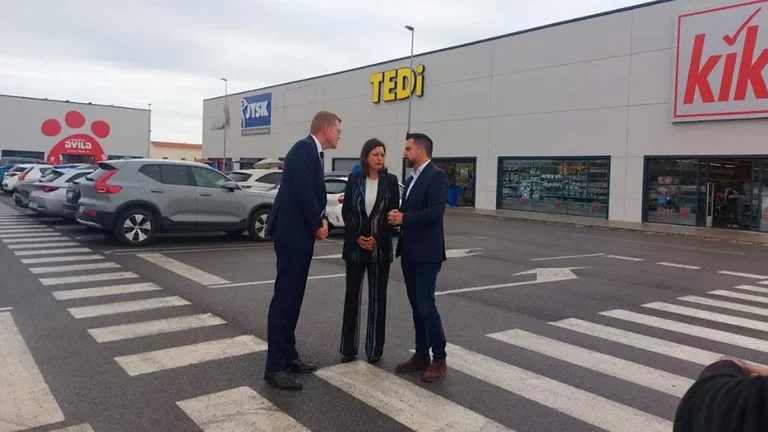 Patricia Cavada, con traje negro, en Zona Franca, tras ella diferentes comercios.