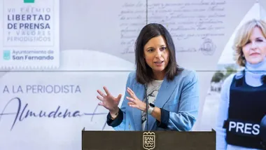 Patricia Cavada, con chaqueta celeste, tras ella, en pantalla, una imagen de Almudena Ariza.