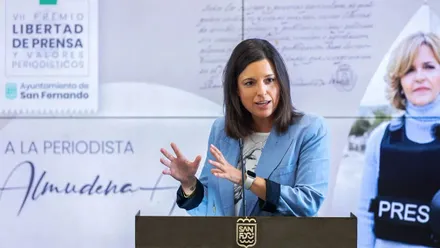 Patricia Cavada, con chaqueta celeste, tras ella, en pantalla, una imagen de Almudena Ariza.