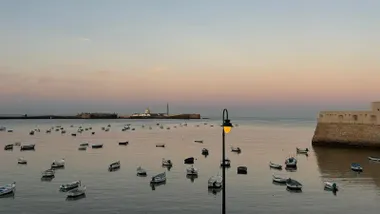 Imagen casi de postal de La Caleta de Cádiz a primera hora de la mañana, con el mar en calma, las barquitas y los dos castillos.
