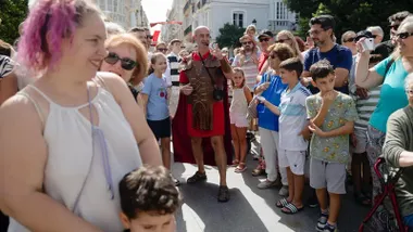 Un actor caracterizado como Julio César representa la animación teatralizada ‘Conociendo Gades’, rodeados de niños y familias que participaron en la actividad.