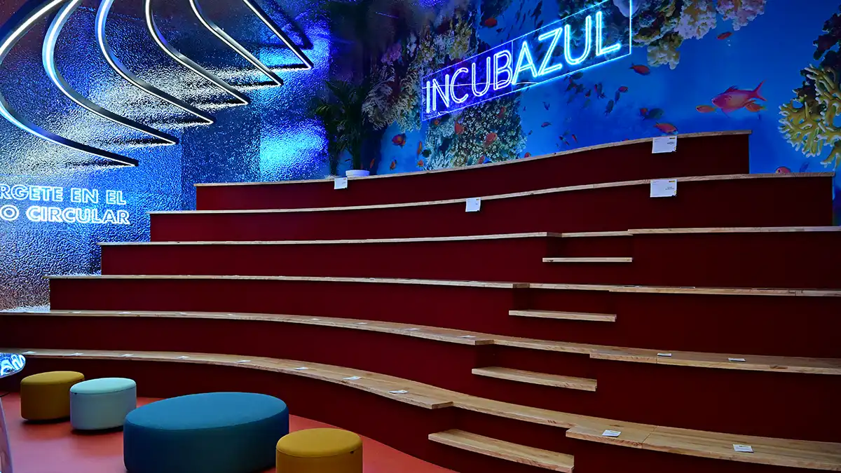 Auditorio con butacas dispuestas en filas frente a un escenario y pantalla de proyección. El espacio es amplio, con iluminación moderna y preparado para conferencias y eventos.