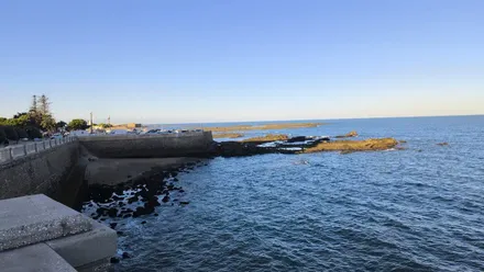 Vista del mar de Cádiz en la zona del Campo de las Balas, con cielo azul despejado y las rocas descubiertas por la marea baja.