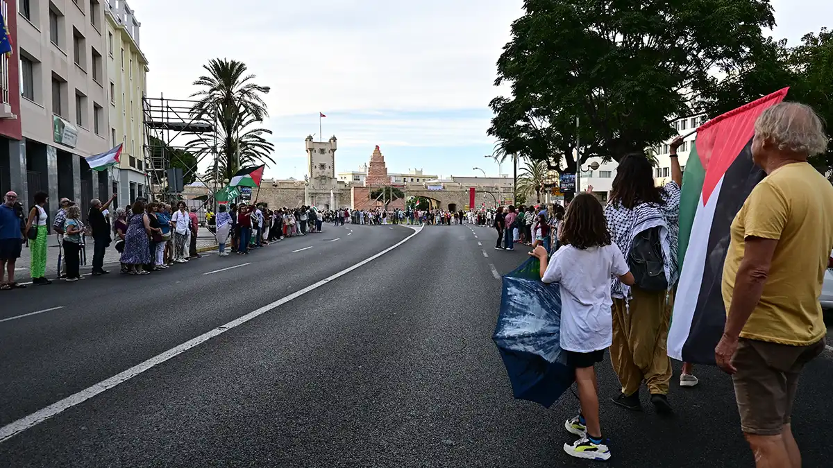 Multitud de personas enlazadas formando una cadena humana con banderas palestinas en Cádiz.