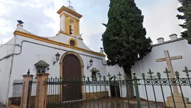 Patio y puerta de entrada, junto a un ciprés y una cruz de mármol de la Capilla del Santo Cristo de Chiclana.