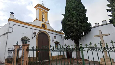 Patio y puerta de entrada, junto a un ciprés y una cruz de mármol de la Capilla del Santo Cristo de Chiclana.