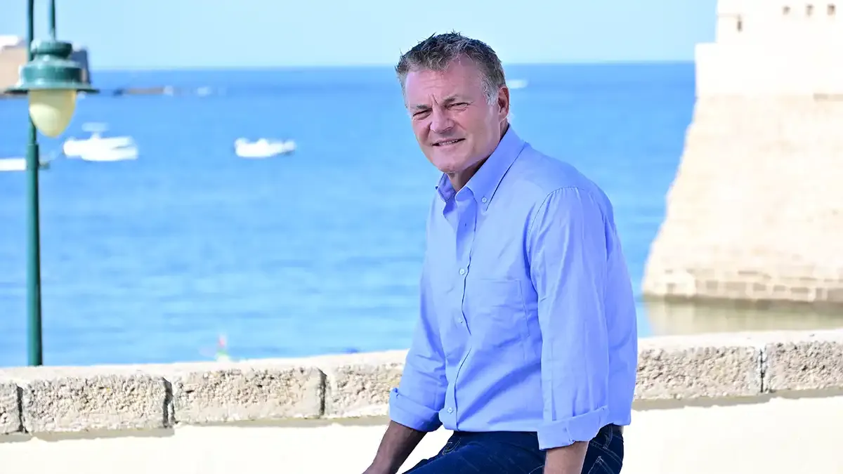 Chris Brancato posa sonriente en el photocall con La Caleta de Cádiz al fondo.