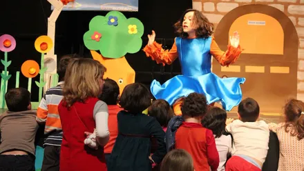 Chica con vestido celeste en un "Cuentacuentos" con niños y niñas.