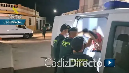 Detenido, con camiseta rosada, siendo introducido en el furgón de la Guardia Civil por varios agentes.