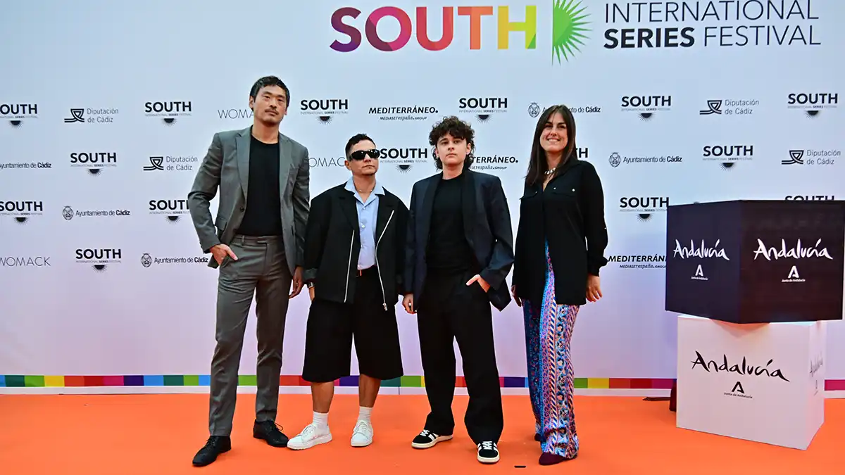 Grupo de tres jóvenes profesionales en la alfombra roja posando.