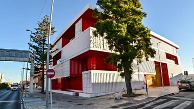 Vista exterior del edificio de Incubazul, compuesto por contenedores marítimos reciclados, con varios niveles y terrazas abiertas. La entrada principal se distingue con ventanales amplios y un diseño moderno.