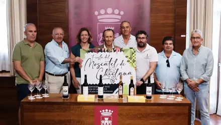 Organizadores y fuerzas municipales posando junto al cartel de la Fiesta del Moscatel en Chiclana.