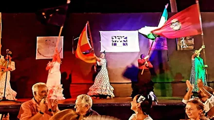 Escenario con mujeres enarbolando banderas en el Festival internacional folklore Ciudad de Cádiz.