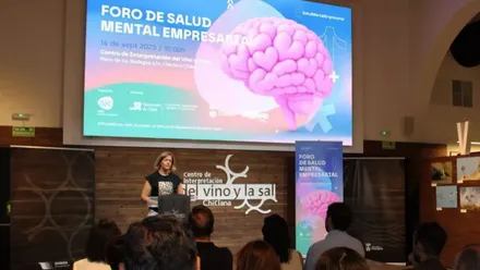 Atril con la delegada y la pantalla de fondo con el Foro de Salud Mental.