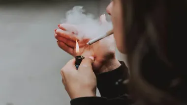 Chica encendiendo un cigarrillo.