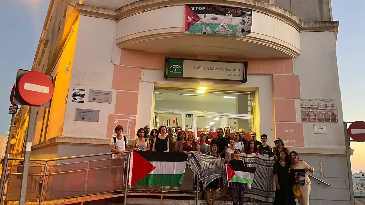 Grupo de docentes reunidos en un aula con pancartas en apoyo a Palestina.