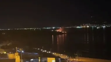 Vista del mar y de las llamas en el Parque del Centenario de Algeciras destacando en la noche.