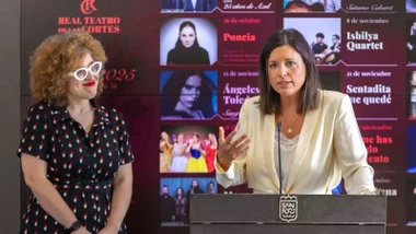Patricia Cavada, con chaqueta clara, y la concejala de cultura, tras ellas el panel con la programación del Teatro de las Cortes.
